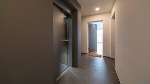 A hallway with a sliding glass door leading to a bright room. The floor is tiled, and the walls are painted in neutral tones. - Vacation Rental City 10 in Massagno (Massagno)