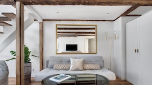 A modern living room with a glass coffee table, a grey sofa, a wooden staircase, and a white wardrobe. - Regent 6- Cozy 1-Bdr Apt with Terrace in the Centre of Copenhagen (København)