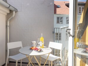 A balcony with a round table, two chairs, a fruit platter, a bottle, and a glass. - Regent 6- Cozy 1-Bdr Apt with Terrace in the Centre of Copenhagen (København)