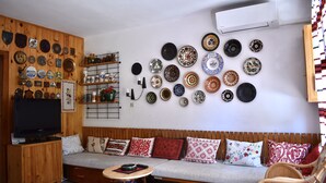 Ein Wohnzimmer mit einer Holzwand, einem Sofa, einem Fernseher und einer Wand mit dekorativen Tellern.