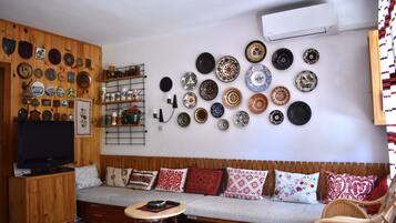 Un salon avec un mur en bois, un canapé, un téléviseur et un mur décoré d’assiettes.