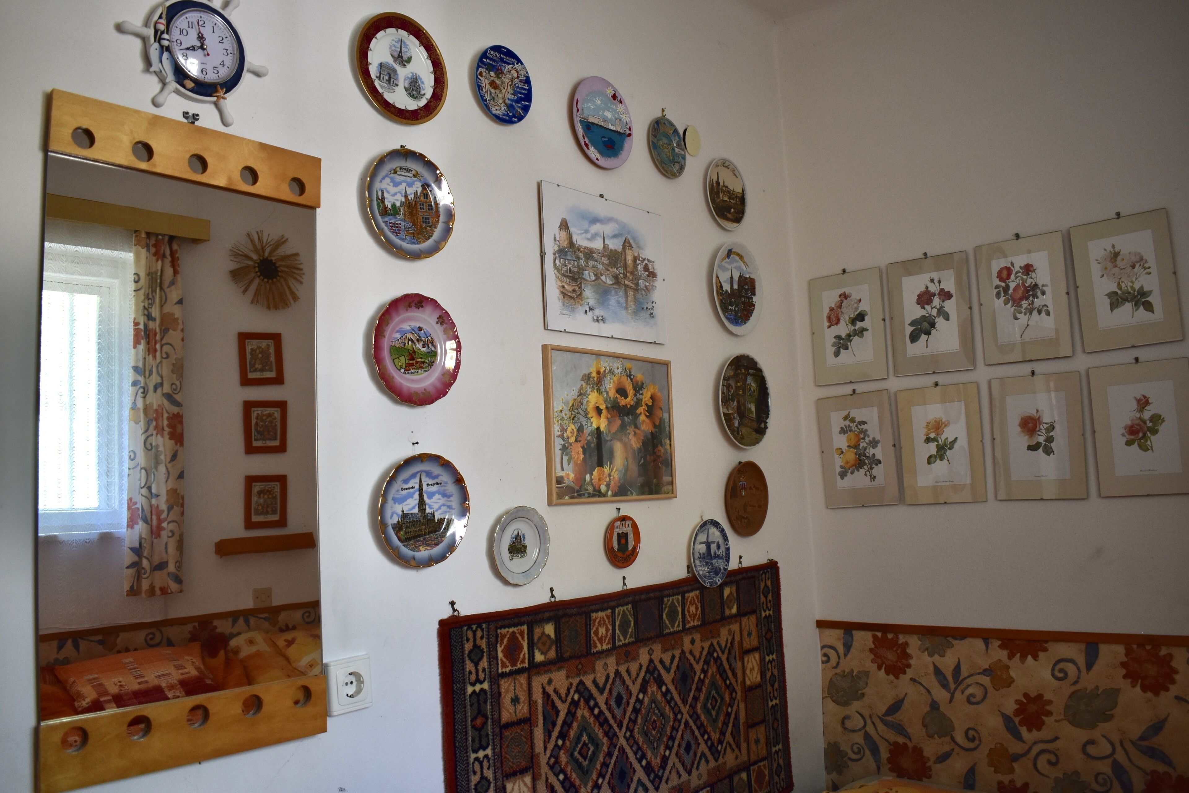 Une pièce comprenant un lit, un miroir et un mur décoré d’assiettes et de tableaux encadrés.