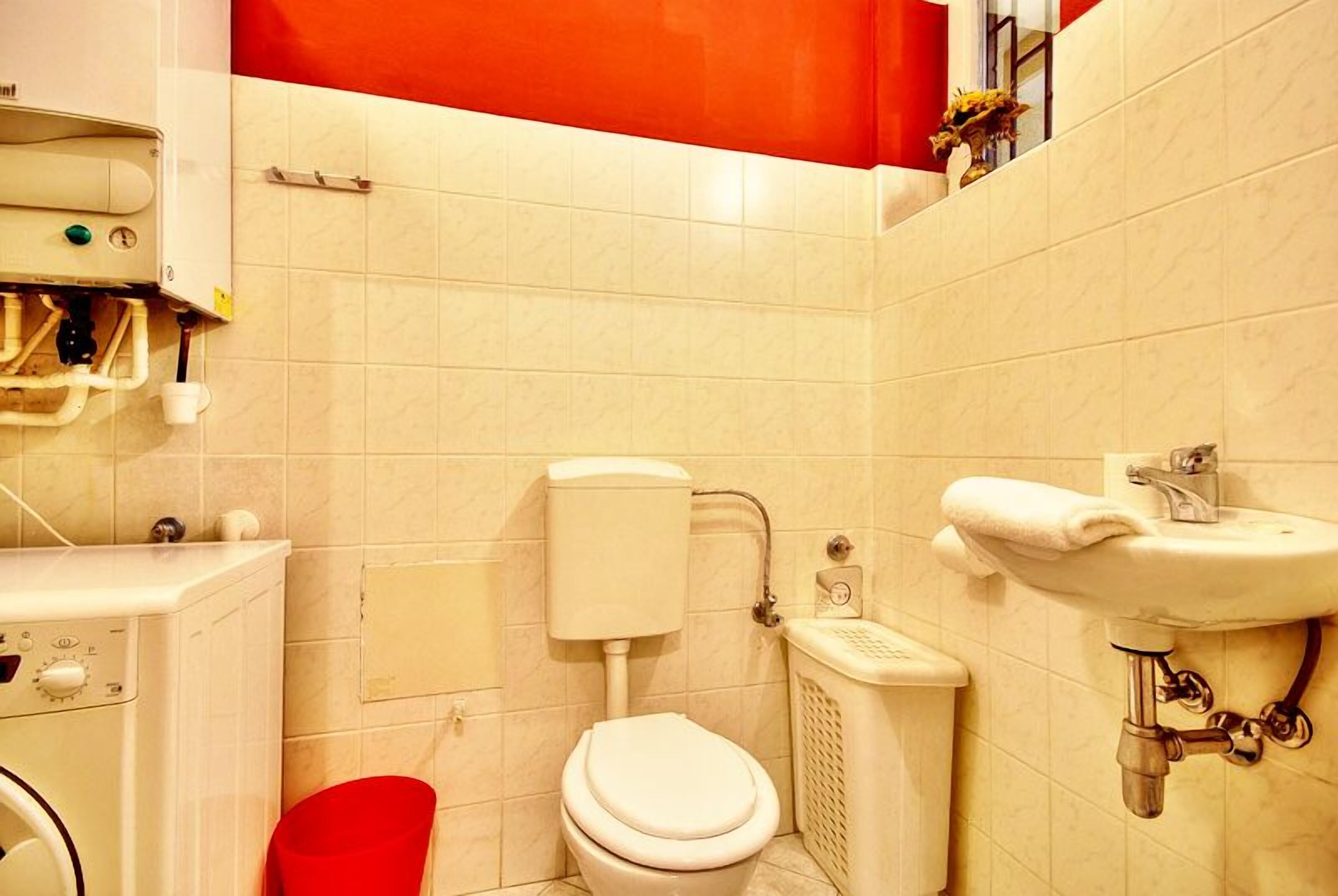 Une petite salle de bain comprenant des toilettes, un lavabo et un lave-linge.