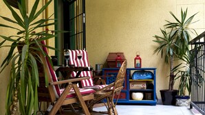 A patio with wicker chairs, a striped tablecloth, and potted plants. - Stunning 2 Double Bedroom Apartment In The Centre Of Budapest (Budapest)