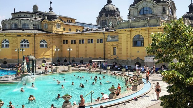 A large outdoor swimming pool surrounded by a yellow building with classical architecture, including domed roofs and columns. - Stunning 2 Double Bedroom Apartment In The Centre Of Budapest (Budapest)