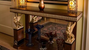 A wooden console table with a vase of flowers, two lit candle holders, and decorative items including a lion statue and a vase with a bird design. - Stunning 2 Double Bedroom Apartment In The Centre Of Budapest (Budapest)