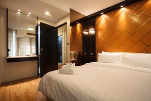 Ein Hotelzimmer mit einem großen Bett, einem Spiegel, einem Holz-Kopfteil und einem kleinen Tisch mit Stuhl.