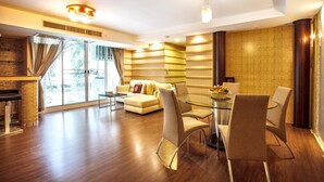 Una sala de estar moderna con una mesa de centro de vidrio, sofás color beige y una zona de comedor con una mesa y sillas de vidrio.