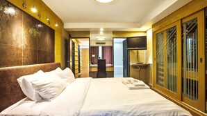 Una habitación de hotel con una cama grande, un escritorio, un televisor y un armario con espejo.