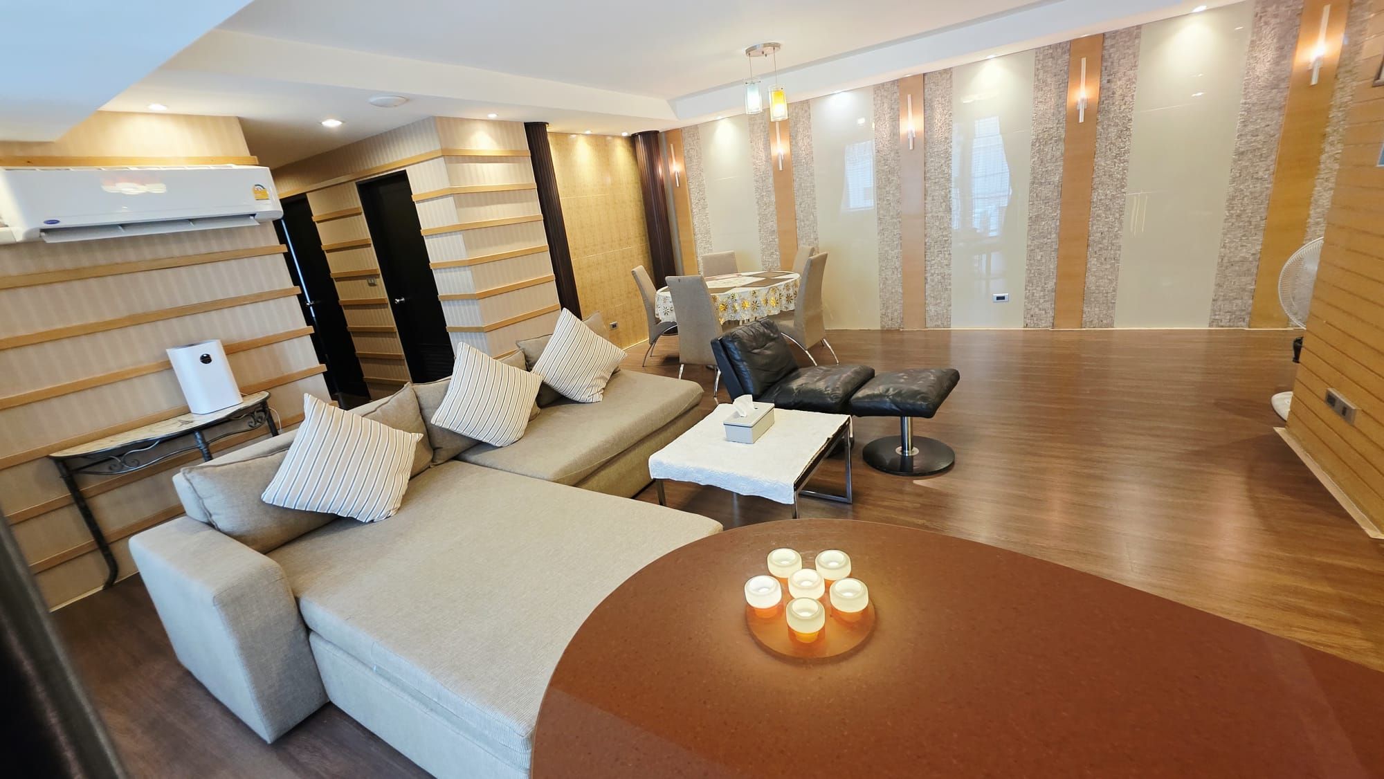 Ein modernes Hotelzimmer mit einer Couch, einem Esstisch und einem kleinen runden Tisch mit Kerzen.
