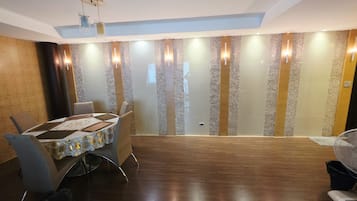 A conference room with a round table, chairs, and a patterned tablecloth.