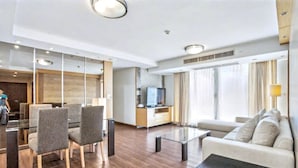 A modern hotel room with a dining area, a sofa, a TV, and a large window. - 3A - Short-Term Rental Allowed - Downtown Bkk Serviced Apartment (Krung Thep Maha Nakhon)