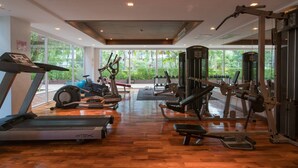 A gym with cardio machines, weightlifting equipment, and large windows offering a view of greenery. - 6-35 - 3 Bdr Condo with Balcony and shared Pool (Tambon Patong)