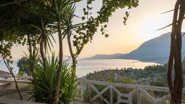 A coastal view with a wooden fence, palm trees, and a mountain in the background. - Apartment with Pool and Panorama View (Koumeika)