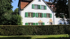 Ein zweistöckiges Gebäude mit grünen Fensterläden, einer weißen Fassade und einem Ziegeldach.