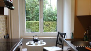Eine kleine Küche mit Fenster, einem Tisch mit Stühlen und einem Herd.