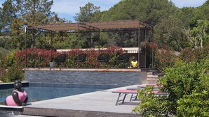 A poolside area with a pergola, outdoor seating, and a statue. - Les Jardins De Santa Giulia - Charmante chambre d'hôte (Porto-Vecchio)
