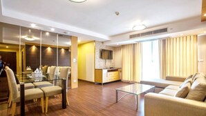 Une chambre d’hôtel moderne dotée d’un coin repas, d’un canapé, d’une télévision et d’un coin cuisine.