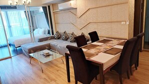 Ein modernes Wohnzimmer mit einer Couch, einem Glastisch und einem Esstisch mit Stühlen.