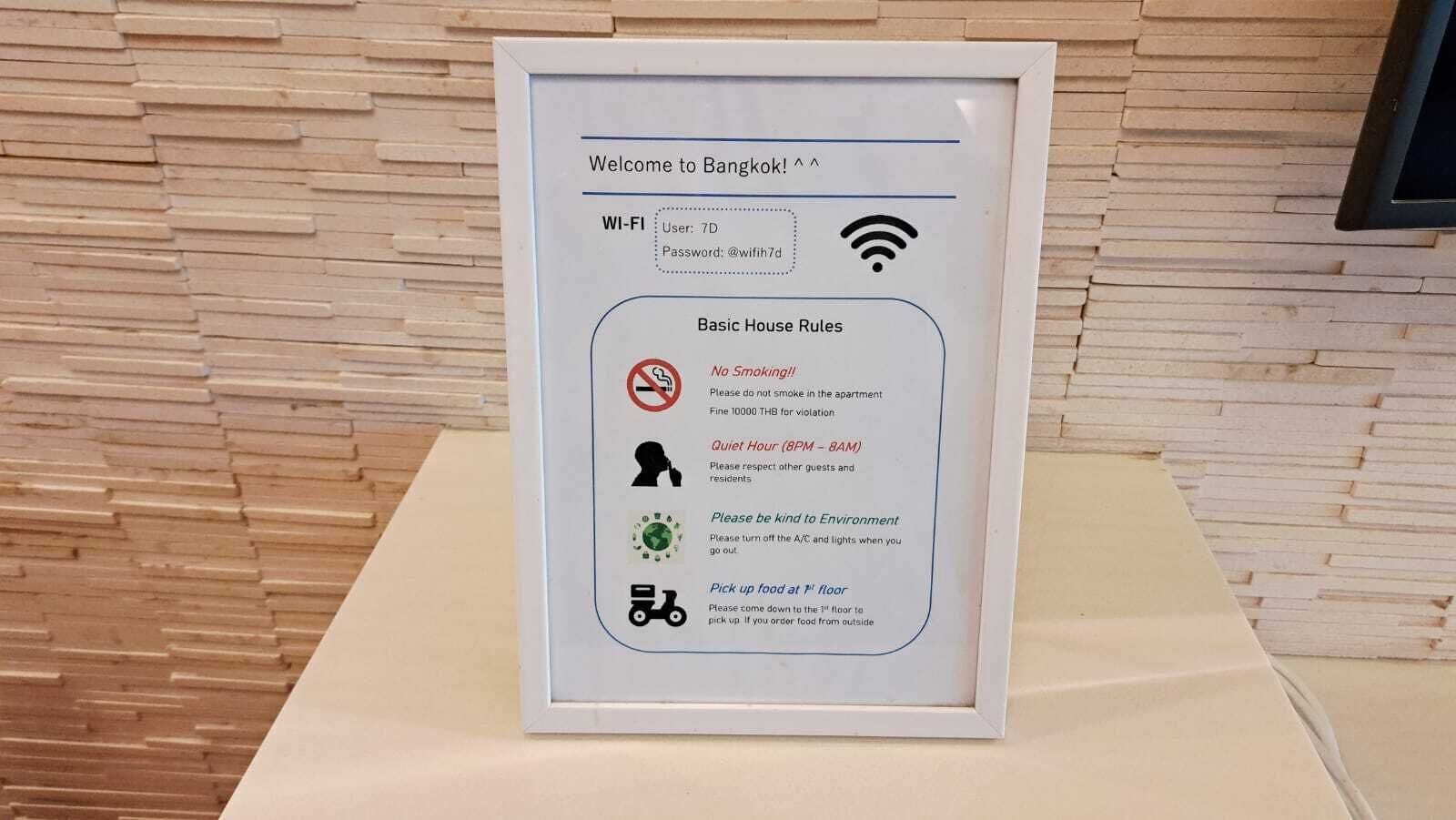 A framed sign with Wi-Fi details and basic house rules for a Bangkok hotel.