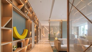 Een modern interieur met een lange gang, houten schapunits en een grote abstracte sculptuur.
