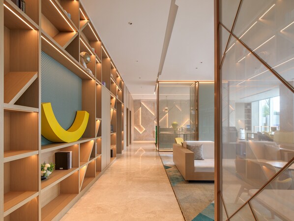A modern interior with a long hallway, wooden shelving units, and a large abstract sculpture. - Holiday Inn Quanzhou Donghai by IHG (Quanzhou)