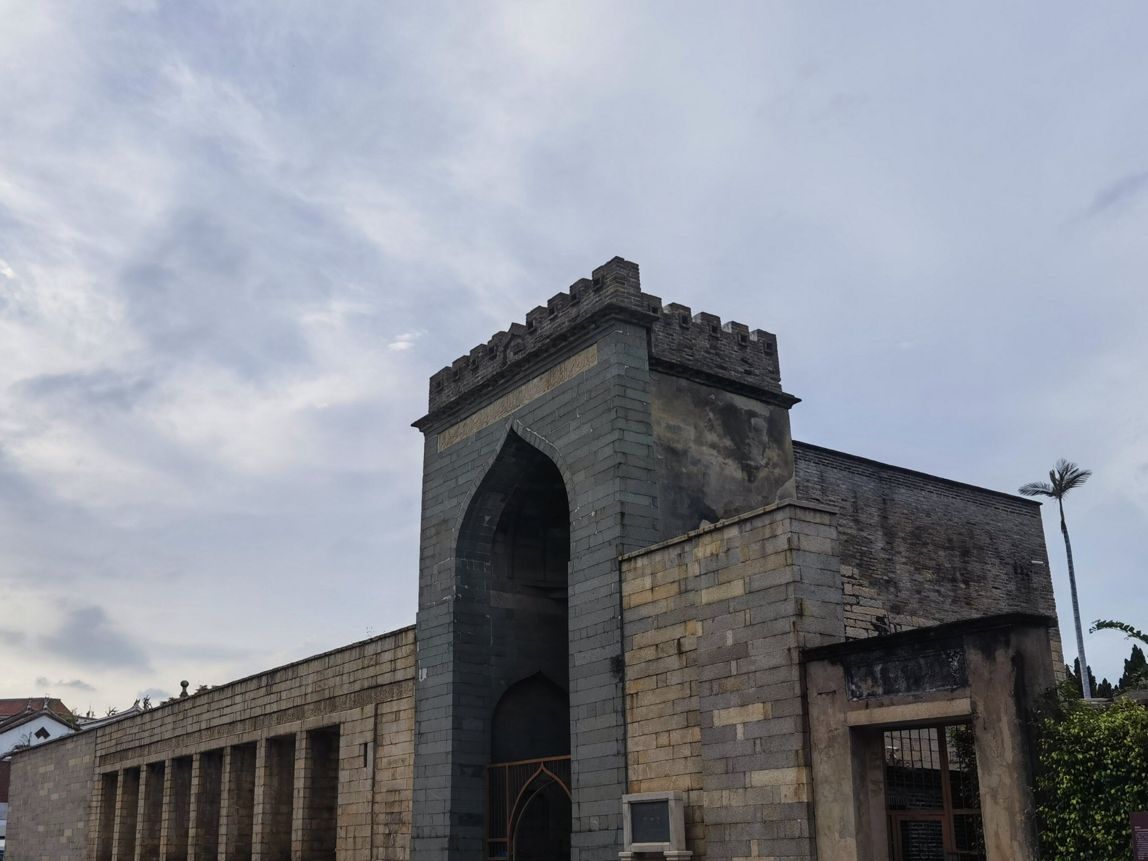 A historic building with a large arched entrance and a tower with battlements.
