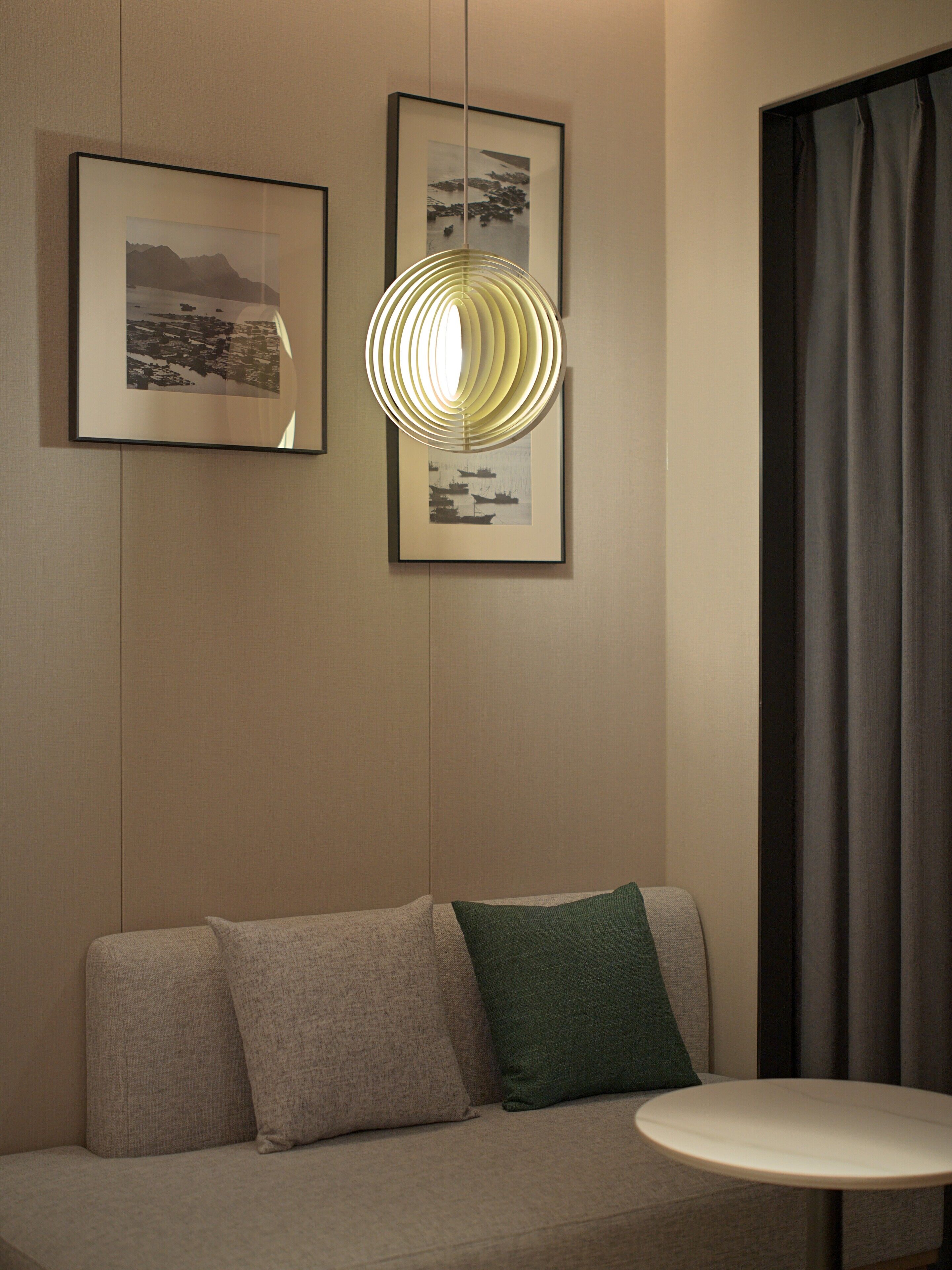 A modern room with a sofa, a small round table, and two framed pictures on the wall.