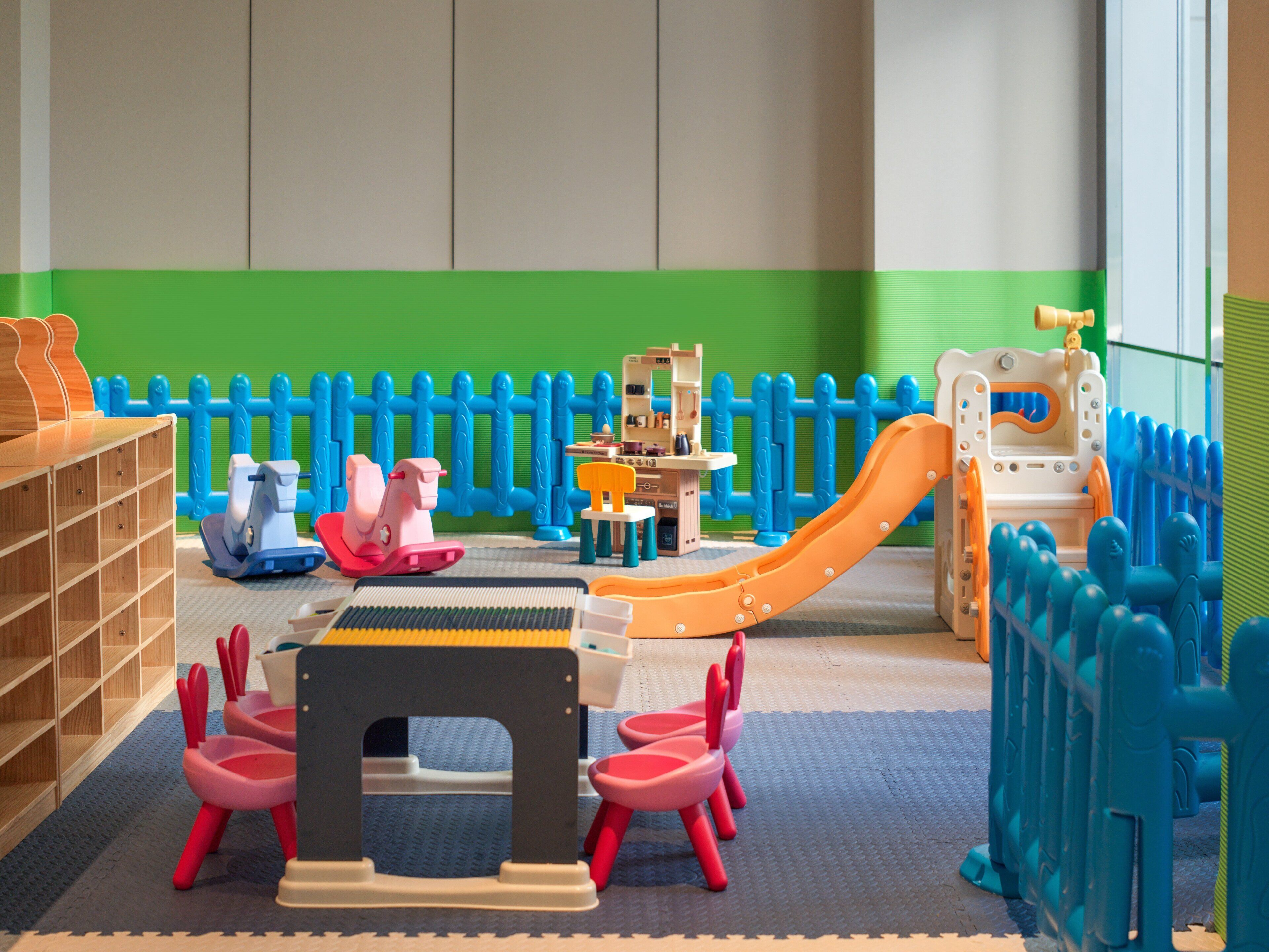 A children's play area with a slide, rocking horses, and a small playhouse.