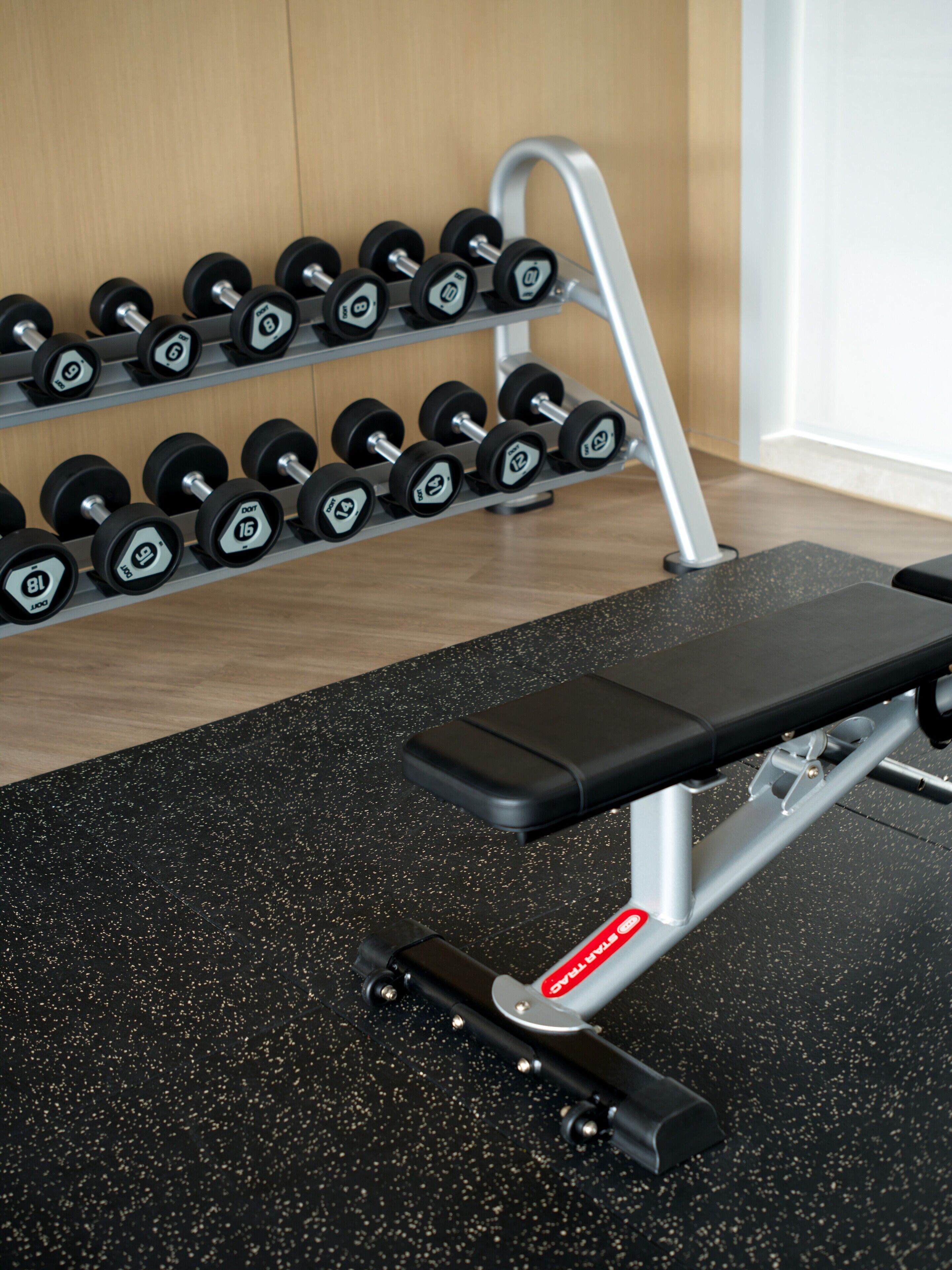 A gym with a bench and a rack of dumbbells.
