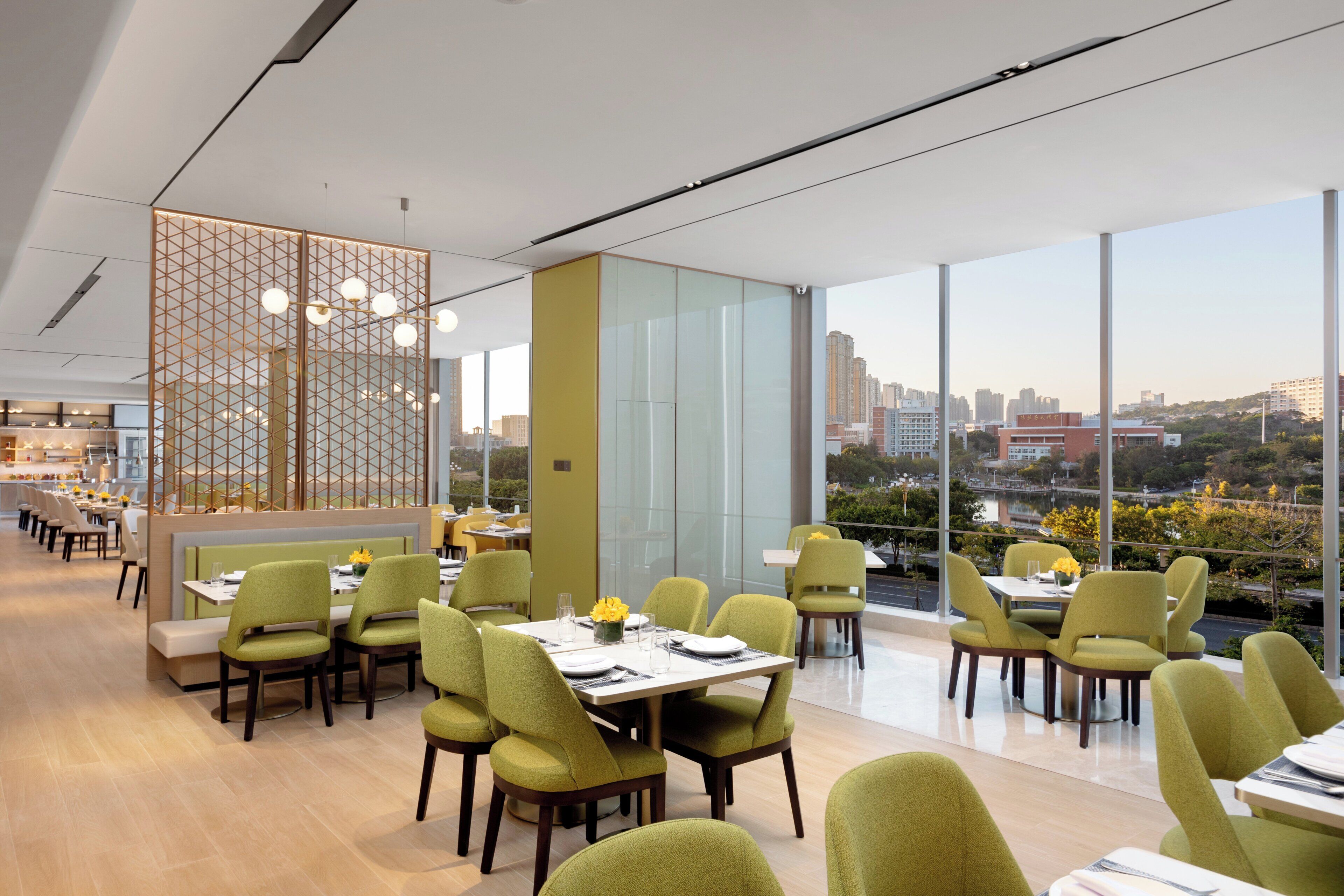 A modern restaurant with high ceilings, large windows, and a city view.