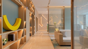 A modern interior with a long hallway, built-in shelving, and a seating area with a glass partition. - Holiday Inn Quanzhou Donghai by IHG (Quanzhou)