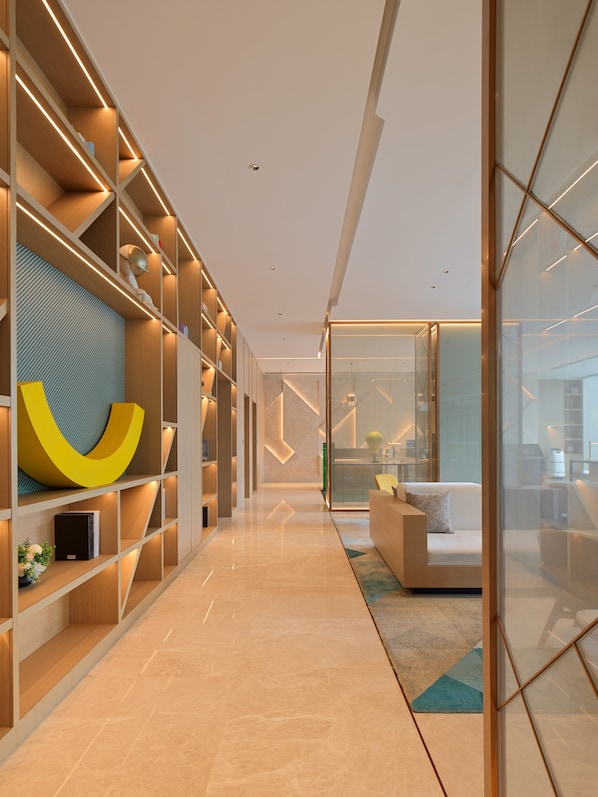 A modern interior with a long hallway, built-in shelving, and a seating area with a glass partition. - Holiday Inn Quanzhou Donghai by IHG (Quanzhou)