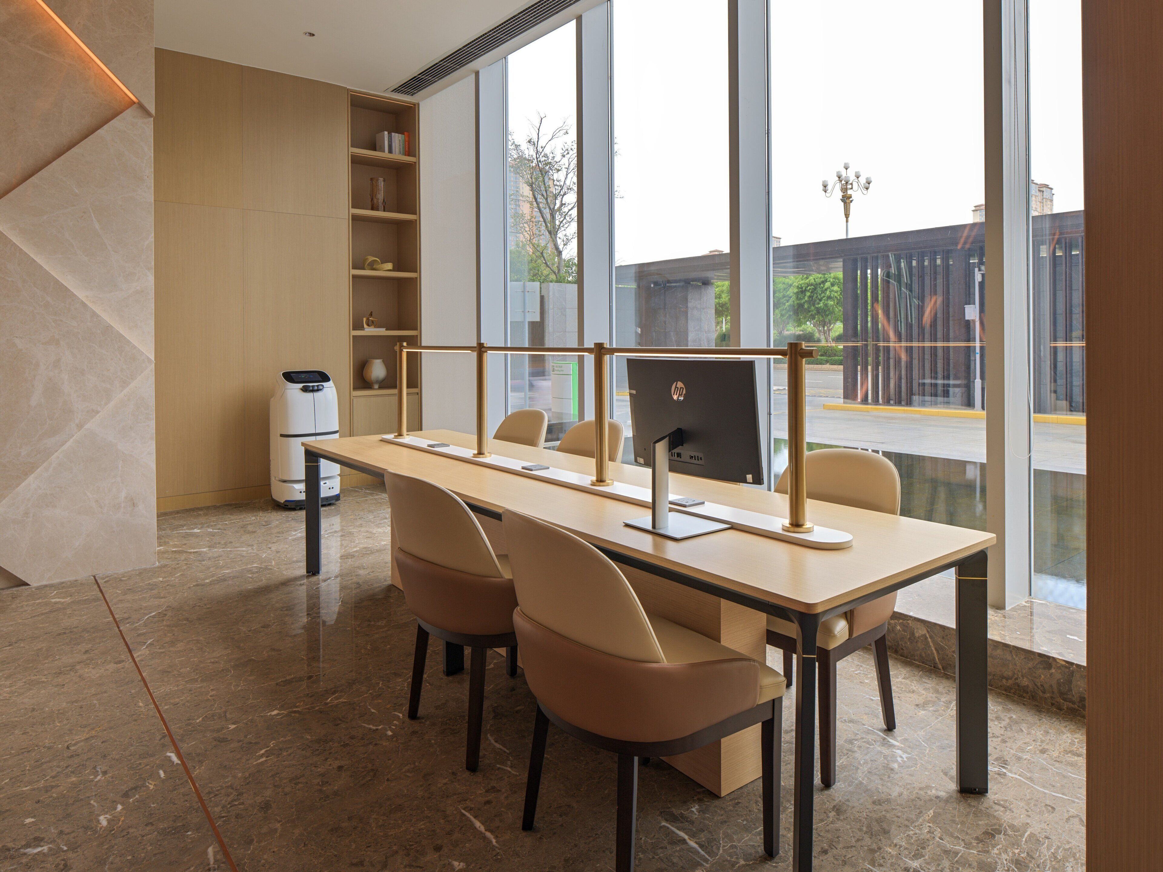 A modern office space with a long table, two chairs, a computer, and a bookshelf.