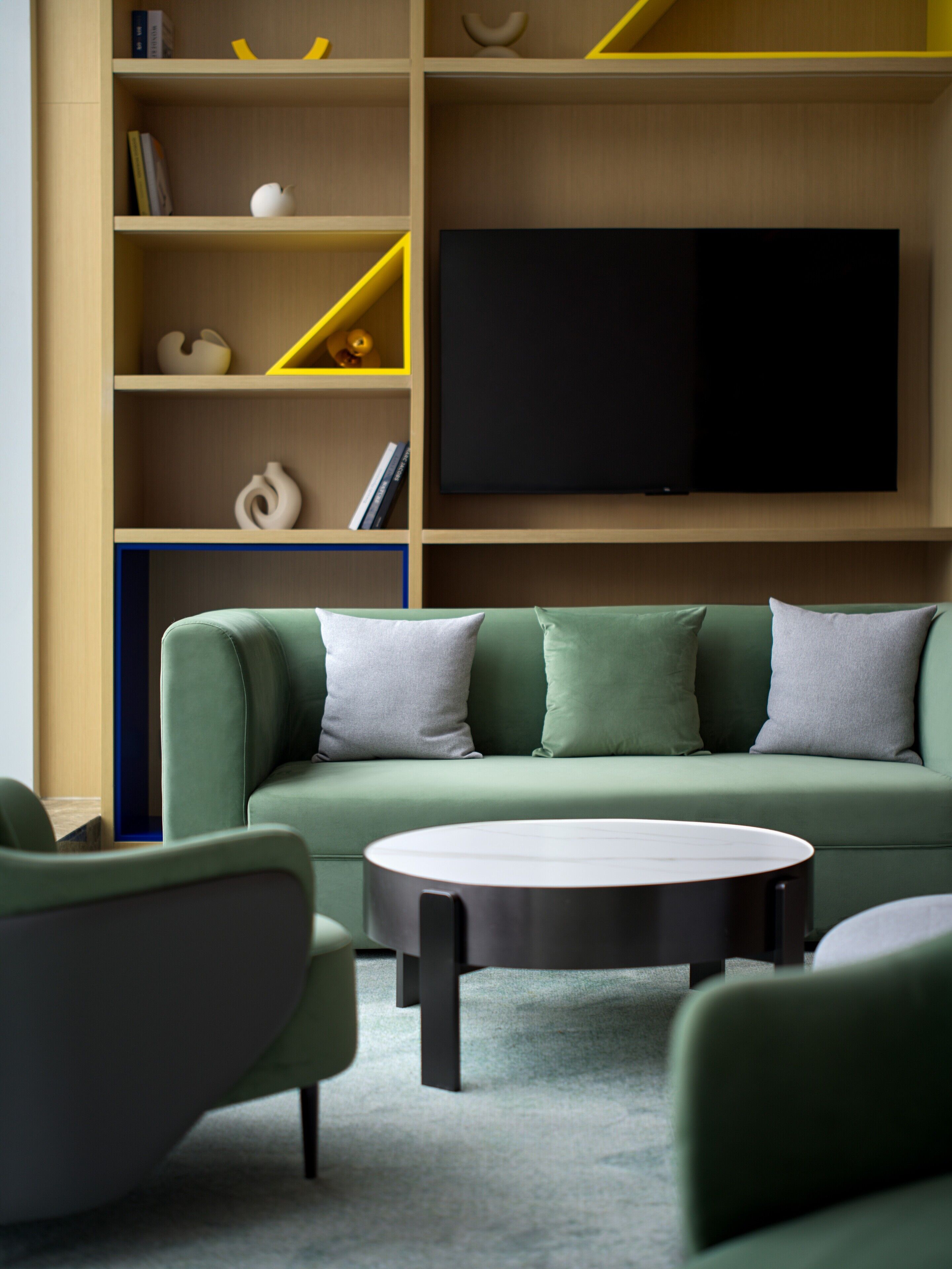 Een moderne woonkamer met een groene bank, een flatscreen televisie en een salontafel.