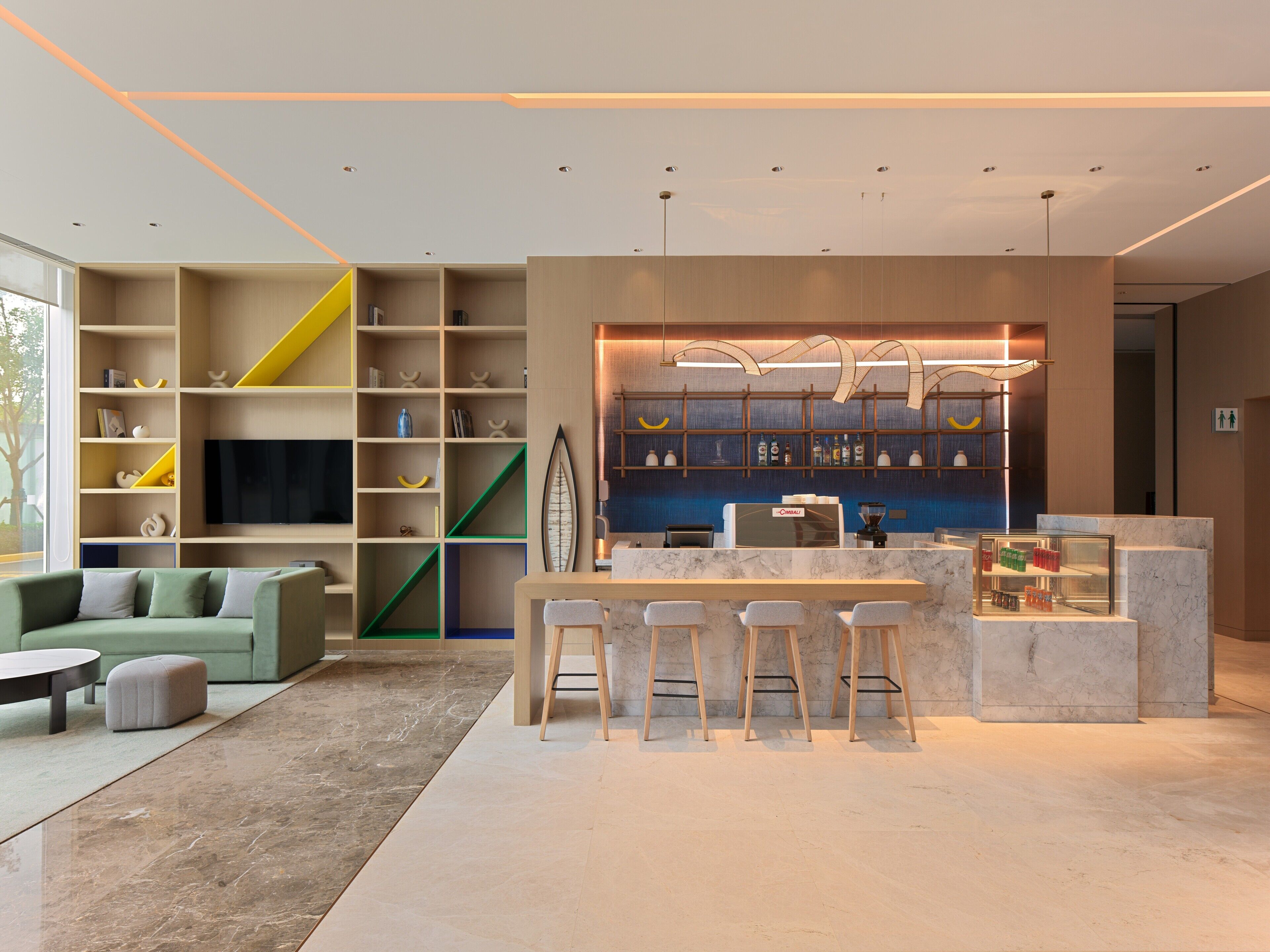 A modern bar area with a counter, stools, and a variety of bottles.