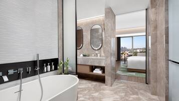 A modern bathroom with a freestanding bathtub, a vanity with a mirror, and a view of the city through large windows.