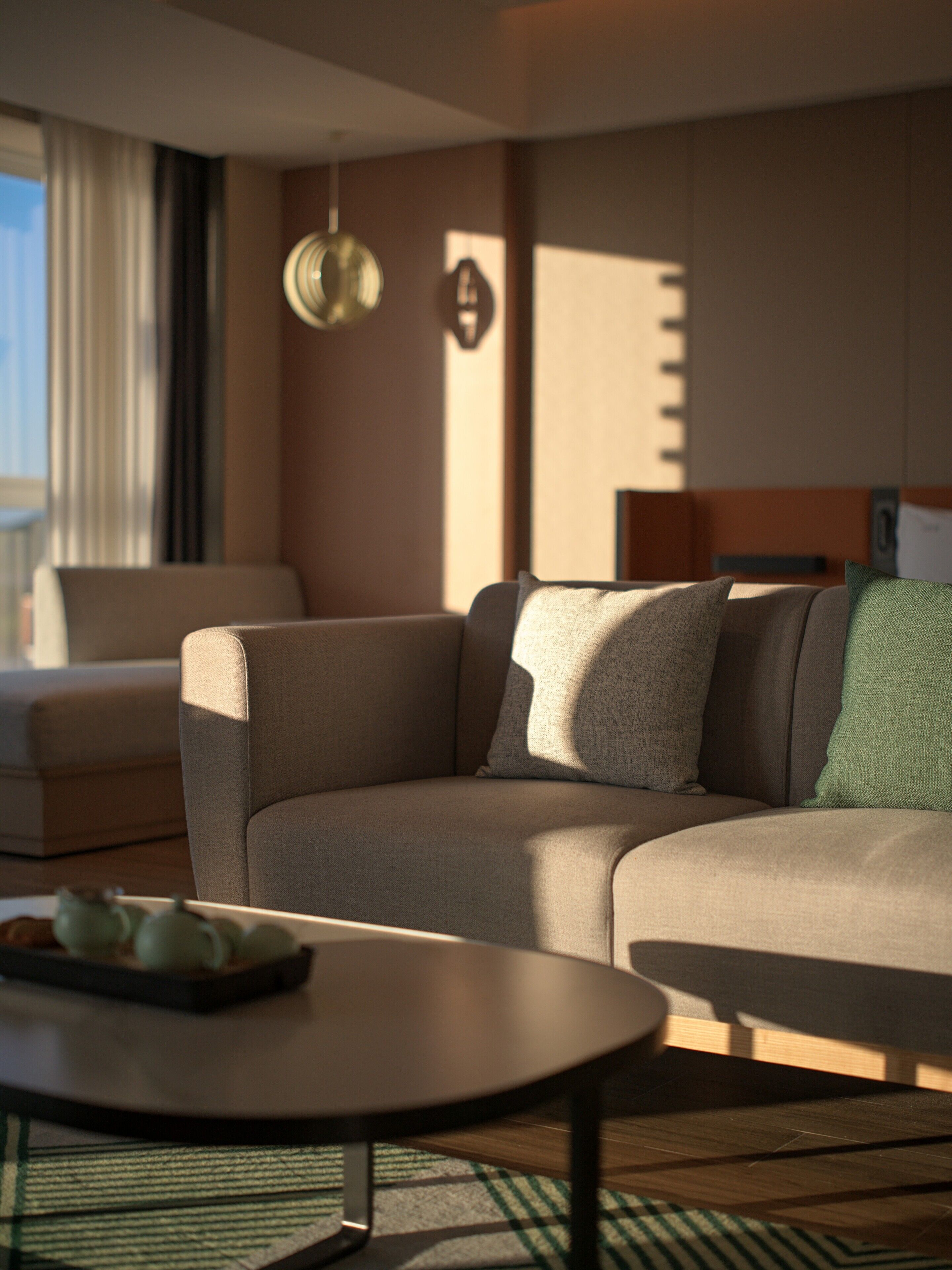 A modern hotel room with a sectional sofa, a small round table, and a view of the outdoors.