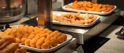 A buffet with various food items, including fried snacks and pastries, arranged on trays.