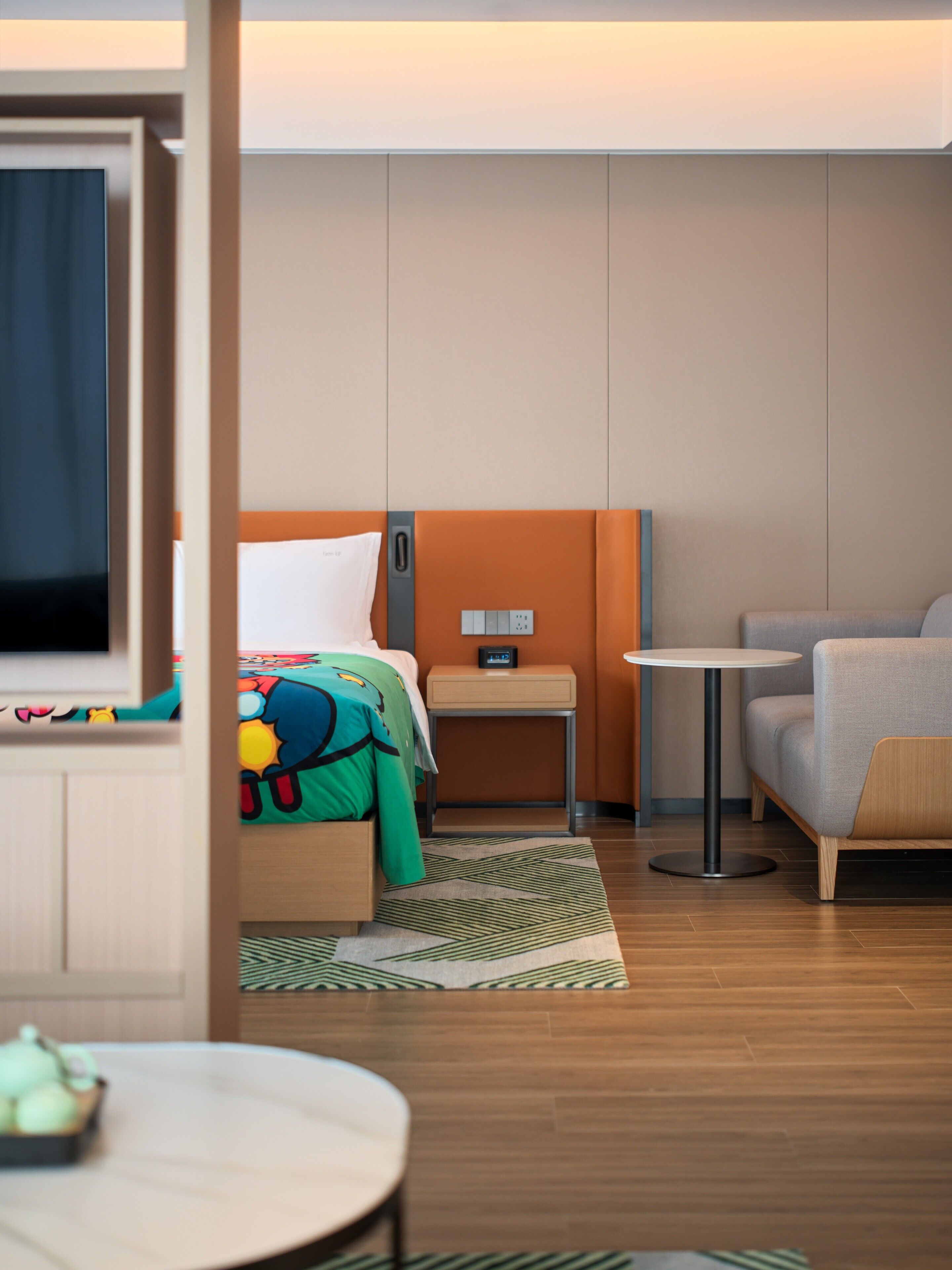 Et hotelværelse med seng, sofa, lille bord og fjernsyn.