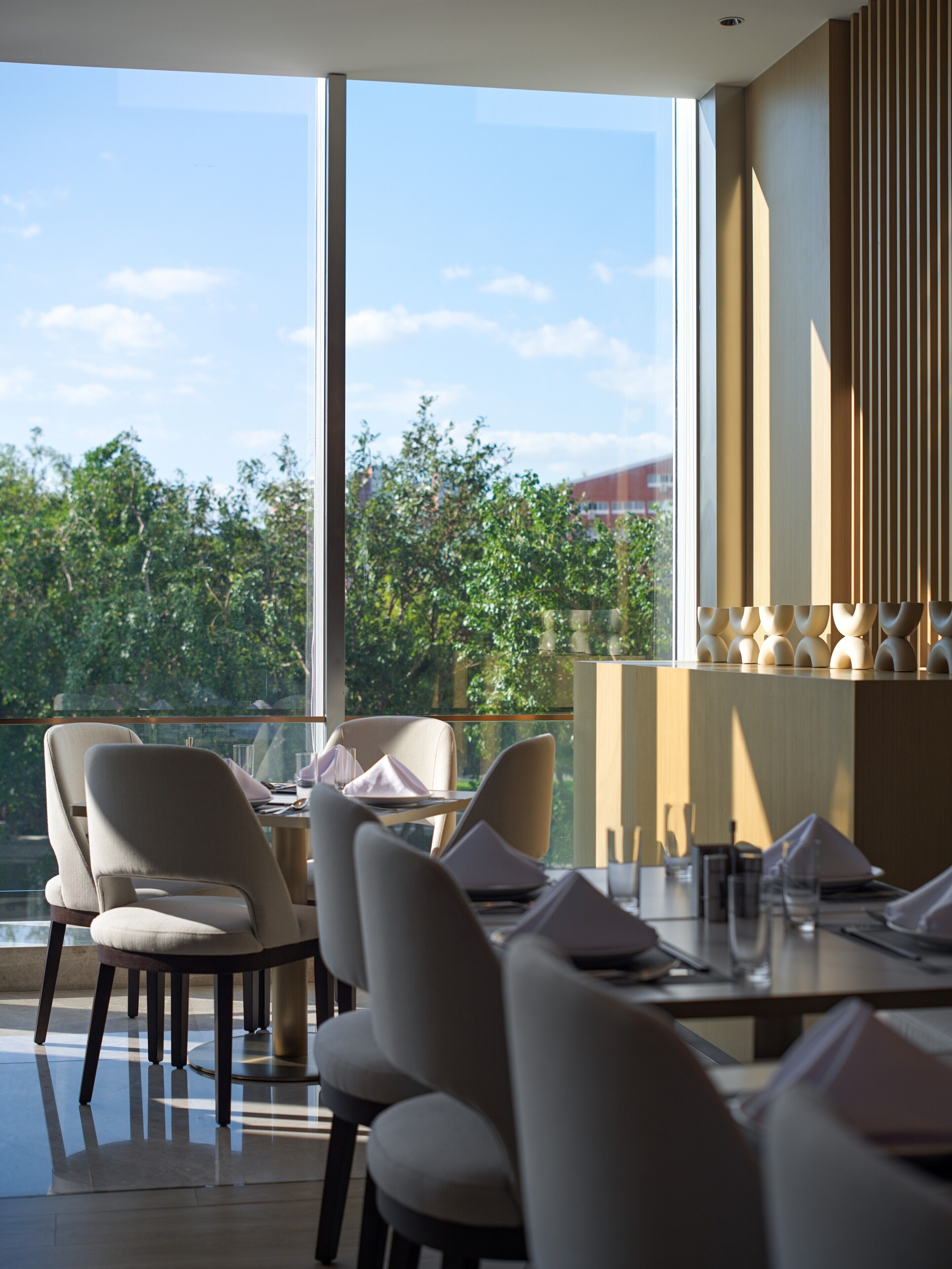 A dining area with a view of greenery and a building in the distance.