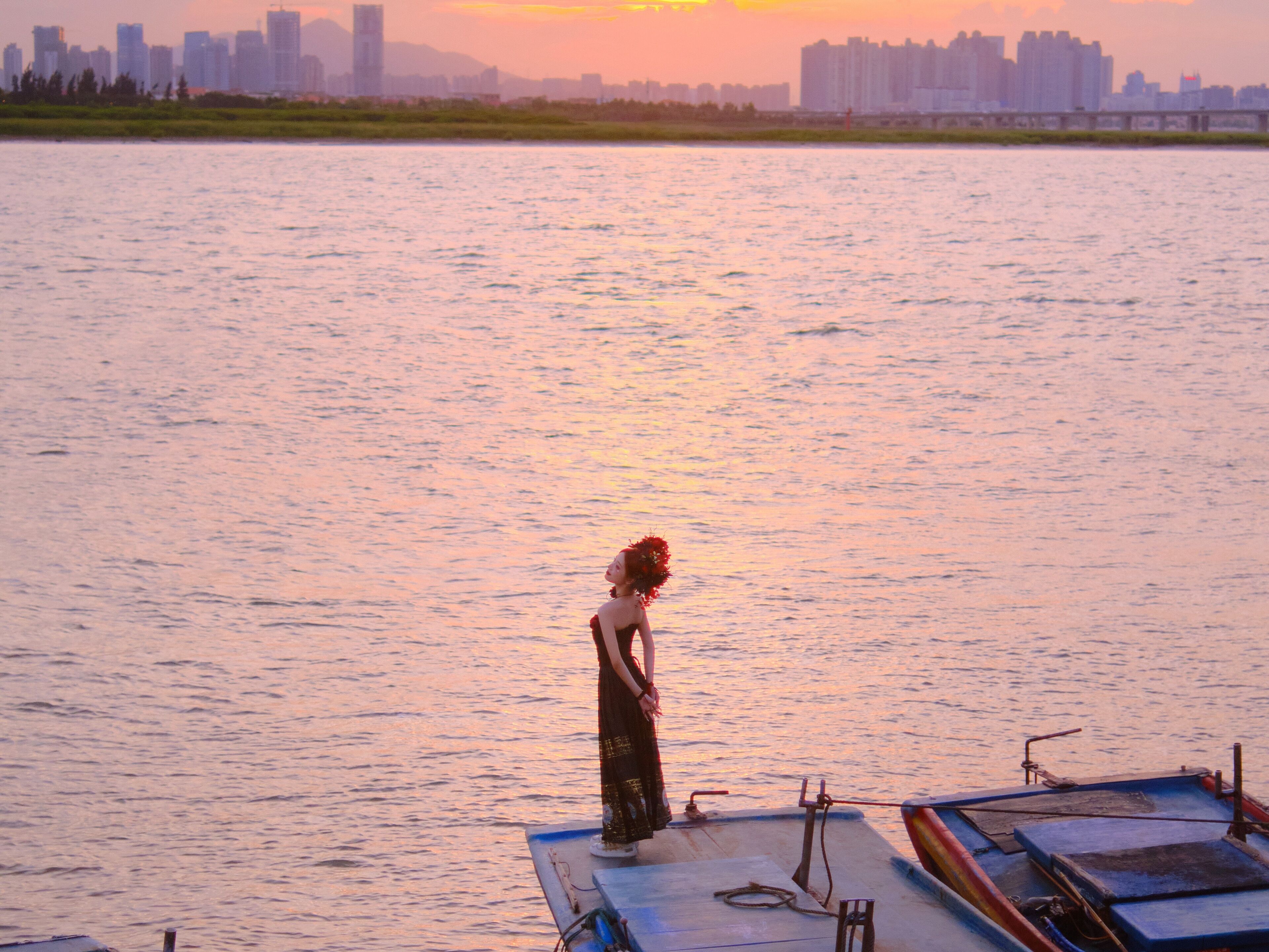 A person standing on a dock with a city skyline in the background.