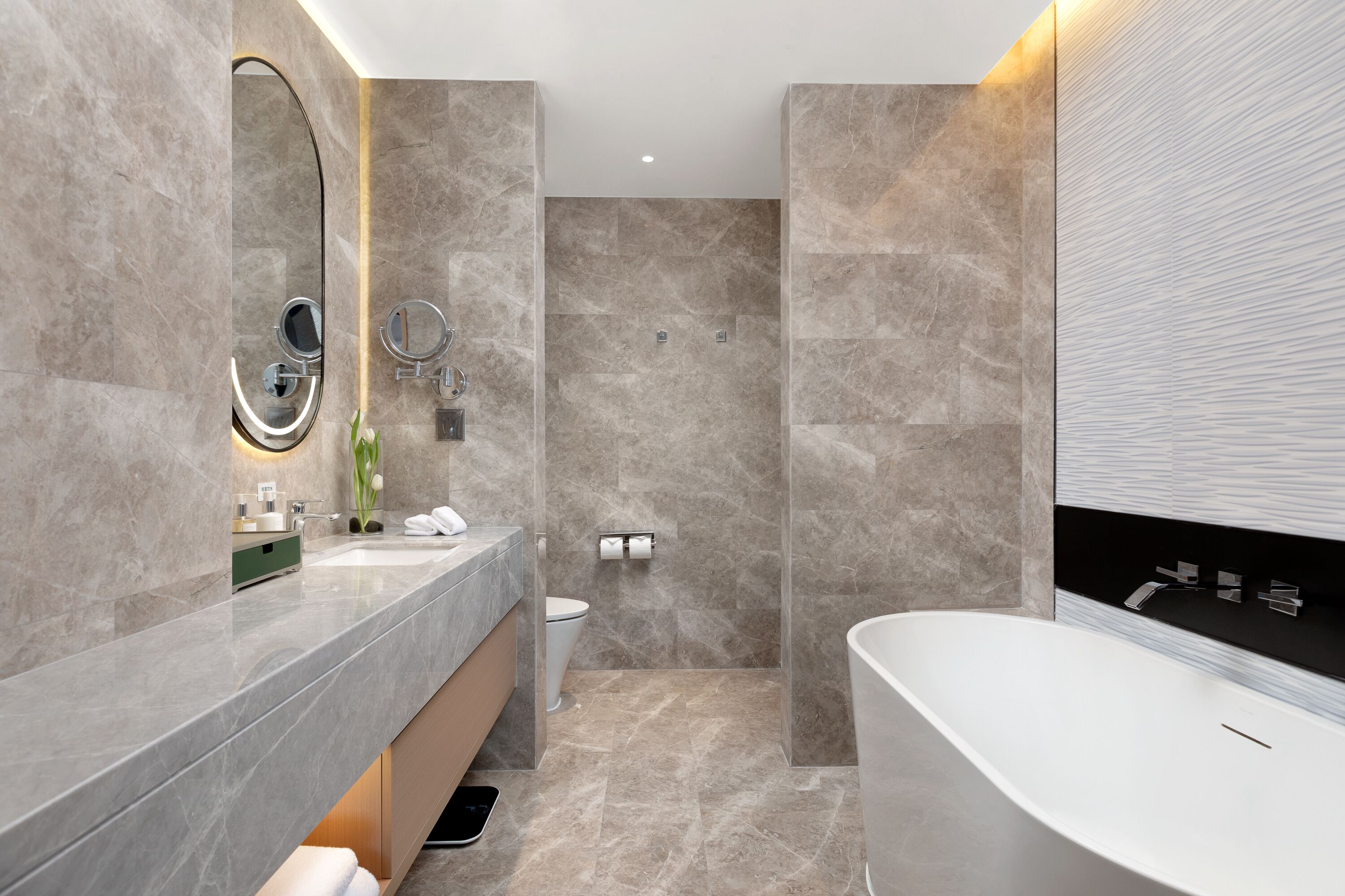 Un baño moderno con un espejo grande, una bañera y un inodoro.