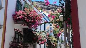 A narrow street with white buildings, pink bougainvillea, and a red column. - Lovely Studio With Private Terrace And Ocean View by El Sirocco - 100 stairs (Lomo Quiebre)