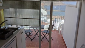 A balcony with a view of the sea and a patio area with chairs and a table. - Lovely Studio With Private Terrace And Ocean View by El Sirocco - 100 stairs (Lomo Quiebre)