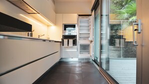A modern kitchen with built-in appliances, a glass door leading to a balcony, and a clean, minimalist design. - Lakeview Motta Penthouse in Melide (Melide)