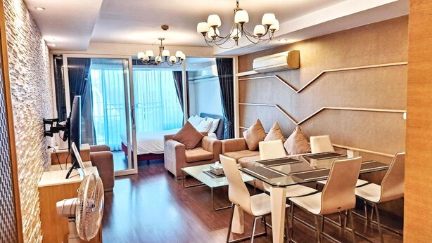 Une chambre d’hôtel moderne dotée d’un coin repas, d’un lit avec des rideaux, d’une grande fenêtre et d’un lustre.