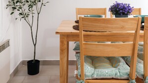 Un coin repas avec une table en bois, des chaises, une plante en pot et une œuvre d’art encadrée accrochée au mur.