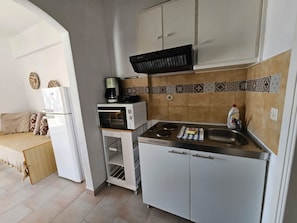 Une cuisine compacte équipée d’un four à micro-ondes, d’une machine à café, d’une cuisinière et d’un évier.