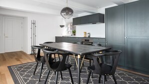 Et moderne køkken med et mørkegråt skab, et rundt spisebord med sorte stole og en tæppe med et mønster.